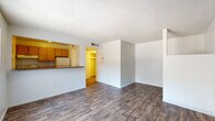 Located at 1150 E Irvington Rd in Tucson, Arizona, this single-floor unit offers a straightforward and functional layout designed for comfortable everyday living. Throughout the space, durable wood-look flooring in a rich, dark tone provides a cohesive and easy-to-maintain surface, complemented by clean white walls and textured ceilings.

The open living area serves as the heart of the unit, offering a generous amount of space with a large window that allows natural light to fill the room and provides views of the surrounding exterior. The layout flows naturally toward the kitchen, which is connected to the living area via a convenient pass-through counter with a breakfast bar. The kitchen features warm wood-toned cabinetry, a white refrigerator, and additional counter space, making it both practical and accessible.

A dedicated bedroom area with white walls and matching wood-look flooring offers a quiet, private retreat, with a structural column adding a subtle architectural element to the space. A closet area is also accessible nearby, providing useful storage.

The bathroom is well-appointed with a wood-toned vanity, granite-style countertop, a single sink, a lighted mirror, and a separate toilet area. Additional closet space adjacent to the bathroom adds further storage convenience. Overall, the unit presents a clean, move-in-ready environment suited for practical living in Tucson.