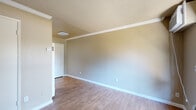 Located at 3280 Blue Ridge Circle in Stockton, California, this single-floor unit offers a practical and efficiently designed layout comprising a main living area, kitchen, and bathroom. The living space features warm wood-look laminate flooring that extends throughout, neutral beige walls, crisp white baseboards, and crown molding that adds a clean, finished look. A textured popcorn ceiling and flush-mount lighting fixtures are consistent throughout the unit. A window at the front of the living area allows natural light to filter in while providing a view of the surrounding greenery, and a wall-mounted air conditioning unit ensures year-round comfort. The galley-style kitchen is thoughtfully equipped with white cabinetry offering ample storage above and below, a granite-look countertop with a stainless steel sink, and white appliances including a gas range, microwave, and refrigerator. The flooring continues seamlessly from the living area into the kitchen. The bathroom includes a single-sink vanity with a marble-look countertop, white cabinetry, a toilet, and a shower-tub combination enclosed by sliding glass doors with chrome framing. The overall ambiance is clean, neutral, and move-in ready, making efficient use of the available space.