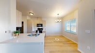 Located at 2700 Pierce Pkwy in Springfield, Oregon, this two-bedroom, one-bathroom residence offers a thoughtfully designed single-floor layout. Light wood-style flooring runs throughout the home, lending warmth and continuity to every room.

The kitchen is a standout feature, showcasing light wood cabinetry, clean white countertops, and black appliances including a range, microwave, and refrigerator. A peninsula with a built-in sink extends into the adjoining dining area, functioning as both a prep space and a casual gathering spot. The dining area is brightened by a chandelier and large windows that let in generous natural light and offer views of the surrounding neighborhood.

A glass-paneled entry door further enhances the bright, airy feel of the living spaces. Both bedrooms are finished in neutral tones with light wood flooring, and the primary bedroom includes a dedicated closet with built-in shelving. Windows with blinds provide natural light and privacy in each room.

The bathroom is finished with a distinctive patterned tile floor, a wood-toned vanity with a white countertop, and a shower with a curtain enclosure. The clean, modern aesthetic is consistent throughout the home, making it a well-appointed and functional residence in Springfield.