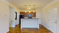 Located at 1300 Community Way in Lancaster, Ohio, this single-floor residence offers a well-designed, open-concept layout that seamlessly connects the living and kitchen areas. Rich hardwood-style flooring flows throughout the main living spaces, creating a warm and cohesive aesthetic.

The kitchen is a standout feature, centered around a granite-topped peninsula illuminated by a trio of pendant lights. Warm-toned wood cabinetry provides generous storage, while black appliances — including a refrigerator, electric range, and built-in microwave — offer a sleek, functional contrast. A stacked in-unit washer and dryer is conveniently accessible just off the kitchen area.

The spacious living room benefits from large windows that invite natural light and offer views of the surrounding community. Crown molding adds a refined architectural detail to this area.

The bedroom is a generously sized, carpeted room with a window providing additional natural light. The primary bathroom is equipped with a single-sink vanity featuring rich wood cabinetry, a sliding glass walk-in shower, and direct access to a walk-in closet with wire shelving. A second bathroom includes a single-sink vanity and hardwood-style flooring, providing practical convenience for guests or additional occupants.