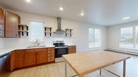 Located at 1530 First Ave N in Moorhead, MN, this one-bedroom, one-bathroom unit offers a thoughtfully designed layout across a single floor. The open-concept kitchen and living area serves as the heart of the unit, featuring warm-toned wood cabinetry, white countertops, and a full suite of stainless steel appliances including a refrigerator, electric range, dishwasher, and microwave. A sleek stainless steel range hood anchors the cooking area, while open shelving with black metal brackets adds a modern, industrial touch. Recessed lighting and multiple windows allow natural light to fill the space, enhancing the clean, bright aesthetic throughout. Light wood-tone luxury flooring runs seamlessly through all rooms, contributing to a cohesive and contemporary feel. The bedroom is a calm, neutral retreat equipped with a ceiling fan, a baseboard heating unit, and a window overlooking the outdoors. A dedicated closet provides practical storage. The bathroom continues the clean design language of the unit with wood-tone flooring and crisp white walls. The overall ambiance is fresh and modern, making this a functional and inviting space suited for comfortable everyday living in Moorhead, Minnesota.