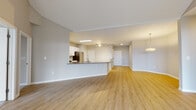 This single-floor residence features a thoughtfully designed open-concept layout that seamlessly connects the living, dining, and kitchen areas. Light wood-tone flooring flows throughout the main living spaces, creating a warm and cohesive aesthetic complemented by neutral gray walls and clean white trim.

The kitchen is well-appointed with white shaker-style cabinetry, a decorative tile backsplash in a geometric pattern, and a full suite of stainless steel appliances including a gas range, over-the-range microwave, and a French door refrigerator. A peninsula with a dark countertop provides additional prep space and separates the kitchen from the open living area. Track lighting and recessed fixtures illuminate the space effectively.

The primary bathroom features a double-sink vanity with white cabinetry, a large mirror, and light wood flooring. A separate water closet adds privacy. A secondary bathroom includes a tiled shower-tub combination and a single vanity. Bedrooms are carpeted for comfort and include window treatments for natural light control. The primary bedroom includes access to a generously sized walk-in closet outfitted with wire shelving and hanging rods on multiple walls.