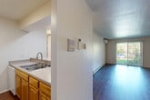 This efficient and thoughtfully designed one-bedroom, one-bathroom unit offers a functional single-floor layout that maximizes every square foot. The living room serves as the central gathering space, featuring rich dark hardwood flooring, a wall-mounted mini-split air conditioning unit, baseboard heating, and a sliding glass door that opens to a view of lush greenery, allowing natural light to fill the room.

The kitchen is positioned adjacent to the living area and is defined by a peninsula counter with a double-basin sink, warm honey-toned wood cabinetry extending to the ceiling, ample counter space, and a full suite of appliances including a refrigerator and range. The pass-through design keeps the kitchen connected to the main living space.

A hallway connects the living area to the private bedroom, which is finished with neutral carpet, a window overlooking mature trees, and baseboard heating. Two closets provide practical storage solutions throughout the unit.

The bathroom is clean and functional, featuring light wood cabinetry with a single-sink vanity, a large mirror, a tub/shower combination, and light-toned flooring. Neutral white walls throughout the unit create a bright, cohesive aesthetic that offers a versatile backdrop for personalization.