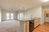 Located at The Bristol in Memphis, Tennessee's 38104 zip code, this single-floor residence features a thoughtfully designed open layout. The kitchen is equipped with stainless steel appliances, including a refrigerator, microwave, and range, complemented by light wood cabinetry and granite countertops that extend to a peninsula with a built-in sink — ideal for casual dining or meal prep. The living areas are finished with plush carpeting and neutral-toned walls throughout, creating a warm, cohesive atmosphere.

Bedrooms are generously sized, each featuring ceiling fans and carpeted floors. One bedroom offers a large window providing natural light, while another opens directly onto a private balcony through French doors. The bathrooms feature granite vanity countertops, light wood cabinetry, hardwood flooring, and walk-in closets with built-in shelving for ample storage.

A dedicated laundry area houses a full-size washer and dryer alongside additional shelving. The unit also includes an electrical panel conveniently accessible within the laundry space. Overall, the residence presents a clean, functional design suited for comfortable everyday living in Memphis.