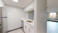 Located at 712 Main Street in the heart of downtown Buffalo, NY, this thoughtfully updated single-floor unit offers a clean, modern aesthetic throughout. Light-toned luxury vinyl plank flooring runs continuously through the open living areas, complemented by neutral gray walls and dark baseboards that create a contemporary, cohesive look.

The open-concept living and dining area is bright and spacious, benefiting from natural light through a large window and featuring track lighting for added ambiance. A baseboard heating system provides efficient warmth throughout. The layout flows naturally into the kitchen, which is well-appointed with crisp white shaker cabinetry, quartz countertops, a stainless steel undermount sink with a pull-down faucet, and a full suite of stainless steel appliances including an electric range, refrigerator, and dishwasher. A light blue accent wall adds a subtle pop of color.

The bedroom area is generously sized with access to a walk-in closet outfitted with wire shelving for organized storage. The bathroom features a full soaking tub with shower, tiled surround with a built-in niche, and clean white finishes throughout. The overall design prioritizes functionality and modern style, making this a well-rounded urban living space in the vibrant Buffalo downtown corridor.