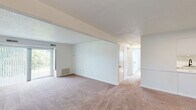 Located at 3554 Weymouth St in Durham, NC, this single-floor, 2-bedroom, 2-bathroom residence offers a comfortable and functional layout. The open-concept living and dining area is carpeted and filled with natural light, with a sliding glass door leading to an outdoor balcony. Textured ceilings and neutral white walls carry throughout, creating a clean, cohesive aesthetic.

The kitchen is well-appointed with white shaker-style cabinetry featuring matte black hardware, light quartz countertops, a stainless steel sink with a black faucet, a stainless steel refrigerator and range, and a dishwasher — all set on durable light wood-tone flooring that extends through the kitchen and hallway areas.

Both bedrooms are carpeted and bright, each with windows that allow natural light. The primary bedroom is generously sized and features a large louvered bi-fold closet that spans most of one wall. A hallway lined with additional louvered closet doors provides ample storage. Both bathrooms are finished with white tile tub-surround showers, matte black fixtures, white vanities, and wood-tone flooring. A utility room and four closets round out the practical storage options throughout this well-maintained Durham residence.