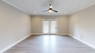 Located at 2121 Langhorne Rd in Lynchburg, Virginia, this thoughtfully designed single-story home offers four bedrooms and two full bathrooms across a comfortable, well-proportioned floor plan. The living room is a bright, welcoming space featuring light hardwood-style flooring, crown molding, recessed lighting, a ceiling fan, and elegant French doors that invite natural light and provide outdoor access. The kitchen is a standout, showcasing grey shaker-style cabinetry with matte black hardware, crisp white countertops, a white subway tile backsplash, and stainless steel appliances including a range and over-the-range microwave — all set on matching light hardwood-style floors. The generously sized primary bedroom features soft carpet, dual windows overlooking greenery, and a ceiling fan. It is complemented by a spacious walk-in closet with built-in shelving and hanging rods. Additional bedrooms are carpeted and equipped with ceiling fans and ample natural light. The bathrooms carry the same cohesive design palette, with grey cabinetry, white countertops, and light wood-style flooring. Neutral warm-grey tones throughout the home create a clean, modern ambiance that is both versatile and inviting.