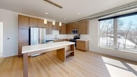 Located at 1880 English St in Maplewood, MN, this three-bedroom, two-bathroom unit offers a modern, contemporary design across a single floor. The open-concept kitchen and living area serves as the heart of the home, featuring light hardwood flooring, warm wood cabinetry, white quartz countertops, stainless steel appliances including a refrigerator, electric range, and microwave, and a central island with pendant lighting. Exposed ductwork adds an industrial character to the space, while large windows invite generous natural light and outdoor views of the surrounding landscape. The primary bedroom is a well-proportioned retreat with hardwood floors and corner windows that frame scenic outdoor views, filling the room with sunlight. The two additional bedrooms feature plush carpeting and bright windows, offering comfortable and versatile spaces. Both bathrooms are finished consistently with tile flooring, a tub-shower combination, a toilet, and a wood-toned vanity with a white countertop. Four closets provide ample storage throughout, and a dedicated laundry area adds everyday convenience. A central hallway connects all rooms efficiently. The overall aesthetic is clean, bright, and functional, with a cohesive modern palette throughout.