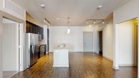 This well-appointed single-floor residence offers a thoughtfully designed open-concept layout that seamlessly connects the kitchen, dining, and living areas. Rich, dark hardwood-style flooring runs throughout the main living spaces, creating a warm and cohesive aesthetic.

The kitchen is a standout feature, centered around a white island with granite countertops and a built-in sink. Dark espresso cabinetry contrasts elegantly with stainless steel appliances, including a refrigerator with ice maker, electric range, and over-the-range microwave. A tile backsplash and pendant lighting over the island add refined detail. Track lighting illuminates both the kitchen and the open living area beyond.

The spacious living room benefits from abundant natural light through large windows and a sliding glass door that opens to a balcony. A ceiling fan enhances comfort and airflow in this area.

Two carpeted bedrooms provide a quiet retreat, each featuring windows with exterior views and generous wall space. The primary bathroom includes a glass-enclosed walk-in shower, dark vanity cabinetry with granite countertops, and hardwood-style flooring. A second full bathroom offers a soaking tub with tiled surround, a matching dark vanity, and access to an in-unit laundry area, adding everyday convenience to this well-finished residence.
