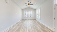 Located in Leland, NC, this single-story home offers a thoughtfully designed layout across two bedrooms and three bathrooms. The kitchen is a standout feature, showcasing gray shaker-style cabinetry, granite countertops, a large center island with a matte black faucet, subway tile backsplash, stainless steel appliances including double wall ovens and a French door refrigerator, and warm hardwood-style flooring throughout. Pendant lighting above the island adds a refined touch. The living and dining areas feature the same light hardwood floors, tray ceilings with beadboard detailing, and an elegant multi-arm chandelier, with windows offering views of the well-maintained neighborhood streetscape. The spacious primary bedroom is finished with plush carpet, elevated ceilings, a ceiling fan, and a double-door closet with Craftsman-style hardware. The secondary bedroom mirrors this comfort with carpet flooring, a ceiling fan, and a large window that fills the room with natural light. The bathrooms are clean and modern, featuring gray cabinetry with black hardware and wood-look tile flooring. The attached garage provides generous storage space with a window and automatic opener. Outside, a concrete driveway leads to a neatly landscaped front yard within a charming residential community.