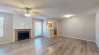 This single-floor residence offers a well-organized and functional layout with consistent wood-look flooring throughout most of the space. The open living area serves as the heart of the home, highlighted by a tiled fireplace framed by a shiplap accent wall, a ceiling fan with light fixture, and a textured ceiling. A pass-through kitchen bar connects the living space to the kitchen, which features warm oak cabinetry, a mosaic tile backsplash, a stainless steel electric range, a white dishwasher, a double-basin sink, and light tile flooring. Natural light enters through a window above the kitchen sink. The bedrooms are generously sized, each equipped with ceiling fans and windows that bring in natural light. Storage is a strong suit, with one bedroom offering a double sliding-door closet and another featuring a spacious walk-in closet with multi-level shelving and hanging rods. The bathroom includes a single-sink vanity with white cabinetry, a yellow countertop, a large mirror, and a shower-tub combination. A dedicated entry area with tile flooring connects the main spaces, and a private exterior door in the living area provides convenient outdoor access.