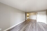 Located at 313 Sandy Ln in Suisun City, California, this single-story 2-bedroom, 1-bathroom home offers a practical and well-organized layout across its single floor. Neutral-toned walls and wood-style laminate flooring flow throughout the main living areas, creating a cohesive and clean aesthetic. The spacious living room is open and bright, with a sliding glass door that leads to a private balcony overlooking lush, tree-lined surroundings, filling the space with natural light. Adjacent to the living area, the combined dining room and kitchen features a galley-style layout equipped with white cabinetry, grey laminate countertops, a stainless steel sink, a full-size refrigerator, and an electric range — offering ample storage and functional workspace. A hallway connects the main living areas to the two bedrooms, each carpeted for comfort and featuring windows that bring in natural light. The primary bedroom includes a mirrored sliding-door closet, while additional closet storage is available throughout. The full bathroom is outfitted with a shower/tub combo, vanity with storage, and a large mirror. A dedicated laundry area and multiple closets round out the home's practical storage solutions.