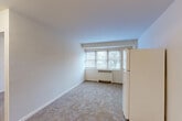 Located at 3435 Holmead Pl NW in Washington, DC, this one-bedroom, one-bathroom residence offers a practical and well-organized layout across a single floor. The open-plan living, dining, and kitchen area forms the heart of the unit, featuring neutral-toned carpet flooring, crisp white walls, and a bank of windows that draw in natural light and offer views of the surrounding neighborhood's mature trees. A white refrigerator anchors the kitchen zone, which transitions seamlessly into the dining and living spaces. Radiator heating units are positioned beneath the windows throughout, providing efficient climate control. The bedroom is a comfortable, private space with its own window, carpeted flooring, and a set of double-door closets providing generous storage. Additional closets — four in total across the unit — ensure ample organizational capacity for everyday needs. A dedicated entrance leads into the unit, offering a clear separation between the living areas and the hallway. The bathroom completes the layout. The overall aesthetic is clean and understated, with a neutral color palette and straightforward finishes that provide a functional, move-in-ready environment in the Columbia Heights neighborhood of Washington, DC.