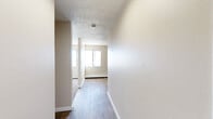 Located in Colorado Springs, Colorado, this single-floor, 3-bedroom, 1-bathroom unit offers a practical and straightforward layout designed to maximize its compact footprint. A central hallway with hardwood-style flooring connects the main living areas, leading to a functional kitchen equipped with warm oak cabinetry, ample upper and lower storage, a black refrigerator, an electric range, and a built-in sink. The kitchen features durable wood-look flooring that complements the cabinetry throughout. Each of the three bedrooms is finished with plush carpet, neutral-toned walls, and ceiling fans with integrated lighting. The spacious primary bedroom offers a generous amount of floor space, while the two additional bedrooms provide comfortable accommodations, each with access to closet storage. Baseboard heating is present throughout the bedrooms, ensuring warmth during Colorado's cooler seasons. Windows in the bedrooms allow for natural light and outdoor views. Textured ceilings are consistent throughout the unit, adding a classic residential character. Two closets provide dedicated storage solutions, and the overall neutral color palette creates a clean, move-in-ready environment throughout the home.