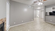 Located at 7795 McCallum Blvd in Dallas, TX, this efficiently designed one-bedroom, one-bathroom unit offers a practical and comfortable single-floor layout. The open-concept main area seamlessly combines the living room, dining area, and kitchen into one cohesive space. Light wood-look flooring runs throughout, complemented by neutral gray walls and a textured ceiling that adds subtle character. Ceiling fans are installed in multiple rooms, contributing to year-round comfort. A standout feature of the living area is a stone-surround fireplace with a glass front, adding warmth and visual interest to the space. The kitchen is defined by a raised granite-style breakfast bar that separates it from the living area. White upper cabinetry, dark countertops, a stainless steel refrigerator, and black appliances complete the functional kitchen. A dedicated pantry provides additional storage. The bedroom is a comfortable, well-lit room with a ceiling fan and a sliding glass door that allows natural light to fill the space. Two closets offer ample storage. The bathroom includes a full tub-shower combination with white tile surround. An in-unit laundry area adds everyday convenience to this well-appointed Dallas residence.