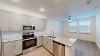 Located at 2600 Illinois Ave in Killeen, TX, this one-bedroom, one-bathroom unit offers a thoughtfully designed layout that maximizes every square foot of its compact footprint. The open-concept kitchen and living area serves as the heart of the space, anchored by a granite-topped peninsula with an integrated sink — ideal for both meal prep and casual dining. The kitchen is outfitted with crisp white shaker cabinetry, a white subway tile backsplash, and a full suite of stainless steel appliances including an electric range, built-in microwave, and dishwasher. Light wood-look flooring runs throughout, lending warmth and visual continuity to the space. A ceiling fan in the living area provides comfort and airflow, while a window invites natural light. The bedroom offers a clean, neutral palette with ample wall space. The bathroom is cleanly finished with granite counters, a walk-in glass shower, and direct access to a well-organized closet with built-in shelving — a practical and efficient storage solution. A hallway connects the rooms seamlessly, contributing to the unit's logical flow. Overall, the space presents a modern, move-in-ready aesthetic with quality finishes throughout.