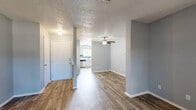 This single-story, 2-bedroom, 2-bathroom home offers a functional and comfortable layout across a well-utilized floor plan. The living room features dark wood-look flooring, a ceiling fan, and an open sightline to the kitchen, creating a connected and airy common area. A sliding glass door fills the space with natural light and provides direct access to a private outdoor patio area.

The kitchen is equipped with gray cabinetry, white countertops, stainless steel appliances including a dishwasher and range, and a distinctive blue tile backsplash that adds a pop of color. A window above the sink allows for additional natural light.

Both bedrooms are carpeted and finished in soft gray tones, offering a cozy atmosphere. The primary bedroom is a generous size and includes a walk-in closet, providing ample storage. Each bedroom is served by its own bathroom, both featuring tub-shower combinations with white tile surrounds and wood-look flooring.

Throughout the home, textured ceilings and neutral gray walls create a cohesive aesthetic. Two hallways and two closets further enhance the storage and circulation of the space, making this home as practical as it is comfortable.
