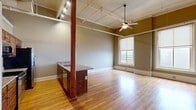 Located at 382 Cherry St in Macon, Georgia, this one-bedroom, one-bathroom loft-style unit offers an open, airy layout with distinctive industrial-chic character. Polished hardwood floors flow throughout the entire space, reflecting natural light that pours in through large, tall windows. The soaring ceilings are accentuated by exposed ductwork, a beadboard ceiling detail, and track lighting, lending the unit a converted-building aesthetic with modern sensibility. A ceiling fan provides a functional focal point overhead.

The kitchen is a standout feature, anchored by a substantial peninsula with granite countertops, an undermount sink, and rich wood cabinetry. Stainless steel appliances — including a range, microwave, and refrigerator with ice maker — complete the well-appointed cooking space. A bold structural wood column adds to the loft's authentic character.

The bedroom is generously proportioned, bathed in natural light from a large window, and benefits from the same high ceilings found throughout. A dedicated closet provides practical storage, while the adjacent full bathroom is clean and functional, featuring a tub-shower combination. The overall ambiance is an appealing blend of historic architectural charm and contemporary urban living.