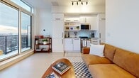 Located at 560 Rideau St in Ottawa, Ontario, this thoughtfully designed unit makes efficient use of its compact footprint across a single floor. The open-concept layout seamlessly connects the living area and kitchen, creating a bright and functional living space. The kitchen features white cabinetry with black hardware, open shelving, a gas range, and a microwave — all designed to maximize utility without sacrificing style. A track light fixture overhead adds a modern industrial touch.

The living area is anchored by clean white walls and light flooring, lending an airy, contemporary feel. A dedicated nook near the floor-to-ceiling windows serves as a versatile workspace, bathed in abundant natural light and offering expansive views of the Ottawa skyline and surrounding neighbourhoods.

The bathroom is finished with large-format neutral stone tiles, a glass-enclosed shower featuring rich marble-toned wall tiles, a wall-mounted vanity, and minimalist black fixtures — creating a clean, spa-like atmosphere.

A balcony extends the living space outdoors, providing elevated panoramic views of the city. Throughout, the design prioritizes clean lines, neutral tones, and smart use of space, making this unit a well-appointed option in the heart of Ottawa.