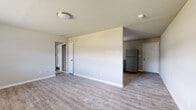 This single-floor space features a clean, modern aesthetic defined by light-toned, wood-look vinyl plank flooring that runs consistently throughout the unit, creating a cohesive and easy-to-maintain interior. Neutral gray walls and white trim provide a fresh, contemporary backdrop across all rooms.

The open living area is well-proportioned, with a partial wall dividing it from the kitchen zone, offering a sense of separation while maintaining an open feel. Flush-mount ceiling fixtures provide overhead lighting, and a ceiling fan is present in one of the rooms, adding both function and airflow.

The kitchen is thoughtfully equipped with gray shaker-style cabinetry, white countertops, a subway tile backsplash, and a full suite of stainless steel appliances including a gas range, built-in microwave, dishwasher, and refrigerator. A window allows natural light into the space.

The bedrooms are generously sized, each featuring windows with blinds that bring in natural light and views of the surrounding area. The bathroom includes a full tub-shower combination with white tile surround, a vanity with storage, and dark floor tile, providing a practical and tidy finish throughout.
