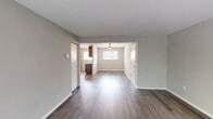 This single-floor unit offers a well-organized layout with distinct living, dining, kitchen, and bedroom areas. The open living and dining space is finished with durable wood-look plank flooring in a warm gray tone, neutral gray walls, and white trim, creating a clean, contemporary aesthetic. A ceiling fan overhead and natural light from a window contribute to a bright, comfortable atmosphere. Vertical blinds on a large sliding glass door in the living area offer outdoor views and additional light control.

The kitchen is well-appointed with dark espresso-toned cabinetry, light quartz countertops, a gray subway tile backsplash, and stainless steel appliances including a refrigerator, gas range, and dishwasher. A window above the sink brings in natural light.

The bedrooms are carpeted for comfort, with neutral walls and windows fitted with blinds. One bedroom features a set of mirrored sliding closet doors providing generous storage, while another includes a standard reach-in closet with a hanging rod. The bathroom is finished with tile flooring, a vanity with a white countertop, chrome fixtures, and a mirror. An in-unit washer and dryer are also present, adding everyday convenience.