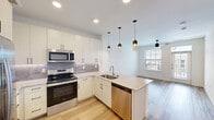This thoughtfully designed one-bedroom, one-bathroom residence in Manor, TX offers a modern aesthetic and efficient layout across a single floor. The open-concept kitchen and living area serves as the heart of the home, anchored by a peninsula with striking granite countertops and an undermount sink. The kitchen is well-appointed with white shaker-style cabinetry, a tile backsplash, and a full suite of stainless steel appliances including a French door refrigerator, electric range, built-in microwave, and dishwasher. Three elegant pendant lights hang above the peninsula, adding a contemporary touch. Light wood-style flooring flows throughout the main living areas, complemented by large windows and a glass-paneled front door that invite abundant natural light. The bedroom is carpeted for comfort, features a ceiling fan, and is served by a generous walk-in closet with built-in shelving and hanging rods. The bathroom offers a clean, spa-like feel with a glass-enclosed shower, granite vanity countertop, and wood-look flooring. Clean white walls and modern finishes create a cohesive, move-in-ready atmosphere throughout this well-appointed Manor home.