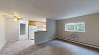 Located at 221 S Oak Ave in Primos, PA, this one-bedroom, one-bathroom unit offers a functional and well-organized single-floor layout. The combined kitchen and living area forms the heart of the space, where a semi-open kitchen is separated from the living room by a half-wall counter. The kitchen features warm honey-toned cabinetry, white appliances including a refrigerator, electric range, and microwave, and light hardwood-style flooring that brightens the space. A window above the sink brings in natural light with greenery views outside. The living room is carpeted and offers a comfortable, open feel, equipped with a wall-mounted AC unit and baseboard heating. Natural light filters in through a window overlooking lush outdoor foliage. The bedroom is a well-proportioned, carpeted retreat with a window framing peaceful outdoor views and baseboard heating. A sliding-door closet with a built-in rod provides practical storage. The bathroom is a standout feature, showcasing a full tub and shower surrounded by large-format white marble-style tiles accented by a decorative blue glass tile border, giving the space a clean, updated aesthetic. A window above the tub adds ventilation and light. The unit also includes a dedicated entry area with a secure door.