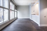 This 2-bedroom, 2-bathroom residence at B3LOW in Memphis, Tennessee blends industrial character with contemporary design across a thoughtfully laid-out single floor. A long, well-lit corridor with pendant lighting and exposed overhead ductwork sets the tone upon entry, establishing the unit's loft-inspired aesthetic.

The kitchen features white shaker cabinetry, light quartz countertops, a sleek tile backsplash in muted gray tones, and stainless appliances, combining both style and functionality. The living area is bathed in natural light from large street-facing windows offering views of the downtown Memphis skyline, with warm hardwood-style flooring extending throughout.

Both bedrooms are generously proportioned, showcasing soaring ceilings, original cast-iron columns, and transom-style clerestory windows that enhance the loft character. The hardwood-style flooring carries through each bedroom, contributing to a cohesive and warm atmosphere.

The bathrooms are finished to a high standard — one features marble-look tile surrounding a soaking tub and shower combo with matte black fixtures, a wood-tone floating vanity, and built-in shelving. The second bathroom offers a clean, modern layout with large-format floor tile and in-unit laundry access. Together, these spaces reflect an urban living experience with refined industrial charm in the heart of Memphis.