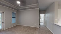 This single-floor residence offers a thoughtfully designed layout with a cohesive neutral color scheme and modern finishes throughout. The open-concept living and dining area is anchored by elegant tray ceilings with crown molding detail, seamlessly connecting to a well-equipped kitchen. The kitchen features white cabinetry, stainless steel appliances including a full-size refrigerator and range, light wood-look flooring, and a peninsula counter that serves as both a workspace and casual dining area, complemented by a pendant light above.

The primary bedroom impresses with its own tray ceiling, ceiling fan, plush carpeting, and direct access to an en-suite bathroom. The en-suite bath is finished with white cabinetry, a stone-look countertop with an undermount sink, and a full tub-shower combination. Additional bedrooms are generously sized, each featuring soft carpeting, ceiling fans, and windows that invite natural light and outdoor views. The secondary bathroom mirrors the same clean, modern aesthetic as the en-suite.

Throughout the home, wide baseboards, soft gray walls, and consistent flooring transitions create a polished and inviting atmosphere. An exterior door off the main living area provides convenient outdoor access, completing this comfortable and well-finished single-level home.