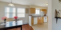 This single-floor residence offers a comfortable and functional layout designed with practical living in mind. The living area features rich hardwood flooring, neutral painted walls, and large windows fitted with blinds that allow for natural light while maintaining privacy. A baseboard heating system runs along the perimeter, ensuring year-round comfort.

The kitchen is well-equipped with warm wood cabinetry, dark laminate countertops, and white appliances including a gas range, dishwasher, and range hood. It opens directly to the dining area, which also enjoys hardwood floors and natural light from adjacent windows — creating a seamless space for both cooking and entertaining.

The bedroom is generously proportioned, accommodating a full-size bed with ease. It features the same hardwood flooring, a double-door closet, and windows that invite natural light. A console table adds a decorative touch to the room.

The bathroom is clean and bright, finished in neutral tones with tile flooring and a tub-shower combination. A window above the tub brings in additional natural light.

Throughout the space, consistent hardwood flooring, soft neutral walls, and thoughtful layouts create a cohesive, welcoming ambiance ideal for comfortable everyday living.