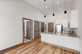 Located at 555 Boulevard NE in Atlanta's vibrant Old Fourth Ward neighborhood, this one-bedroom, one-bathroom unit offers a thoughtfully designed layout with contemporary finishes. Soaring vaulted ceilings throughout the main living area and kitchen create a striking sense of openness and volume well beyond what the footprint might suggest.

The kitchen is a standout feature, designed with white shaker-style cabinetry accented by matte black hardware, a subway tile backsplash, and quartz countertops. A peninsula with an undermount sink provides additional workspace and casual dining potential. Stainless steel appliances — including a refrigerator, electric range, microwave, and dishwasher — complete the modern culinary space. Sleek cylindrical pendant lights hang from the soaring ceiling, enhancing both function and style. Natural light pours in through a large sliding glass door that leads to an outdoor area.

The bedroom features plush carpeting, tall ceilings, and a window that brings in natural light. It connects conveniently to the rest of the unit through a classic two-panel door. The bathroom is clean and functional, with white cabinetry, a quartz-topped vanity, a tiled tub-shower combo, and matte black fixtures and hardware. Wood-look luxury vinyl plank flooring runs throughout the main living areas, tying the space together with a warm, cohesive aesthetic.