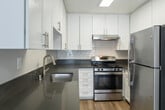 This two-story residence at 1625 W Pacific Coast Hwy in Wilmington, California, offers a thoughtfully designed layout spread across two floors. The kitchen is a standout feature, outfitted with crisp white cabinetry extending to the ceiling, dark quartz-style countertops, a subway tile backsplash, stainless steel appliances including a gas range and refrigerator, and warm wood-look flooring — combining both style and functionality.

Living and common areas on the main floor feature the same wood-look flooring and neutral gray walls, with windows that invite natural light and views of the surrounding greenery. Textured ceilings are found throughout the home.

The upper level includes carpeted bedrooms, each with windows that bring in natural light. One bedroom features a dedicated closet with a full-width hanging rod and built-in shelf, providing ample storage. The angled ceiling in one area of the upper floor reflects the roofline architecture, adding character to the space.

Bathrooms are finished with wood-look flooring, white cabinetry, dark countertops, and chrome fixtures. A full bathroom includes a shower-tub combination, while a separate water closet tucked beneath the staircase offers added convenience. The home's clean, neutral palette and consistent finishes create a cohesive and move-in ready environment.