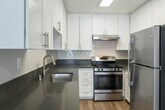 This two-story residence at 1625 W Pacific Coast Hwy in Wilmington, California, offers a thoughtfully designed layout spread across two floors. The kitchen is a standout feature, outfitted with crisp white cabinetry extending to the ceiling, dark quartz-style countertops, a subway tile backsplash, stainless steel appliances including a gas range and refrigerator, and warm wood-look flooring — combining both style and functionality.

Living and common areas on the main floor feature the same wood-look flooring and neutral gray walls, with windows that invite natural light and views of the surrounding greenery. Textured ceilings are found throughout the home.

The upper level includes carpeted bedrooms, each with windows that bring in natural light. One bedroom features a dedicated closet with a full-width hanging rod and built-in shelf, providing ample storage. The angled ceiling in one area of the upper floor reflects the roofline architecture, adding character to the space.

Bathrooms are finished with wood-look flooring, white cabinetry, dark countertops, and chrome fixtures. A full bathroom includes a shower-tub combination, while a separate water closet tucked beneath the staircase offers added convenience. The home's clean, neutral palette and consistent finishes create a cohesive and move-in ready environment.