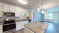 Located at 6701 Fox Rd in Raleigh, NC, this single-floor residence offers a well-designed layout with modern finishes throughout. The kitchen is a standout feature, boasting white shaker-style cabinetry, granite countertops, a subway tile backsplash, and a full suite of stainless steel appliances including a range, microwave, dishwasher, and side-by-side refrigerator. A central island with pendant lighting provides additional prep space and casual seating, flowing seamlessly toward the dining and living areas. The open living and dining space is highlighted by rich hardwood-style flooring, crown molding, a stylish chandelier, a ceiling fan, and a window that brings in natural light. Bedrooms are carpeted for comfort and feature ceiling fans, ample natural light from double windows, and neutral wall tones. The bathrooms are finished with granite-topped white vanities, tiled tub-shower combinations, and hardwood-style flooring, maintaining a consistent, polished aesthetic. A dedicated laundry room accommodates a full-size washer and dryer with built-in wire shelving for storage. The home's cohesive design, quality finishes, and functional floor plan make it an inviting and practical living space.