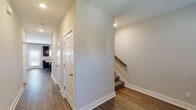This two-floor home offers a thoughtfully designed layout that balances functionality and comfort throughout. The main level features durable hardwood-style flooring that flows through the hallways and kitchen, while a carpeted staircase with a warm wood handrail connects to the upper floor. The kitchen is a standout space, showcasing rich dark espresso cabinetry, light granite countertops, a large kitchen island, stainless double-basin sink, and a full suite of black appliances including a refrigerator, range, and built-in microwave. Additional doors near the kitchen provide convenient pantry and utility access. The upper level is carpeted throughout and features well-sized bedrooms, each with closet storage. One bedroom includes a dedicated walk-in closet outfitted with wire shelving and hanging rods, offering ample organization. The primary bathroom is generously proportioned, with large-format tile flooring, a lengthy double-sink vanity topped with granite, dark cabinetry with brushed hardware, and a full-size soaking tub and shower combination with chrome fixtures. Neutral tones, recessed lighting, and clean white trim unify the home's interior with a modern, move-in-ready aesthetic.