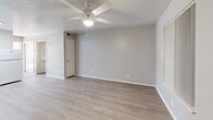 Located at 3135 Comanche Rd NE in Albuquerque, New Mexico, this one-bedroom, one-bathroom unit offers a practical and efficiently designed single-floor layout. Light wood-look flooring runs throughout the entire space, lending a clean, cohesive aesthetic from room to room.

The combined kitchen and living area forms the heart of the unit. The kitchen features gray cabinetry, white countertops, a gas range, a refrigerator, and a stainless steel sink, all illuminated by a recessed skylight-style ceiling fixture. The open connection to the living room creates a functional, easy-to-navigate layout, with the living area benefiting from a ceiling fan and direct access to the entry door.

The bedroom is a well-proportioned private retreat featuring a ceiling fan with light fixture, vertical blinds, and a window that draws in generous natural light, casting bright patterns across the flooring. A mirrored sliding closet door adds both storage and visual depth to the room.

The bathroom is clean and straightforward, featuring a full tub/shower combo, a toilet, and a vanity sink with wall-mounted cabinetry above. Light-toned walls and wood-look flooring maintain the unit's consistent, neutral palette throughout.

Overall, the unit presents a bright, move-in ready space with a cohesive design and practical amenities suited for comfortable everyday living in Albuquerque.