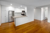 Located on the 10th floor at 111 Market St in downtown Hamilton, this 1-bedroom, 1-bathroom unit offers a well-organized layout that efficiently utilizes its compact footprint. Warm hardwood flooring runs throughout the living areas and bedroom, contributing to a cohesive and inviting atmosphere.

The kitchen is a standout feature, equipped with stainless steel appliances including a refrigerator, electric range, and built-in microwave. Abundant white shaker-style cabinetry extends to the ceiling, providing generous storage. A peninsula counter with a neutral stone-finish surface separates the kitchen from the living area, creating an open-concept feel. A double stainless steel sink with a modern faucet and tiled backsplash complete the space.

The living area benefits from large floor-to-ceiling sliding windows and an additional picture window, flooding the room with natural light and offering elevated city views of Hamilton's downtown skyline. Baseboard heating runs along the perimeter.

The bedroom is a comfortable size, featuring a double sliding-door closet and a window with city views. The four-piece bathroom includes a soaker tub with overhead shower, a white vanity, and wood flooring. A hallway and entrance complete the unit's functional layout.