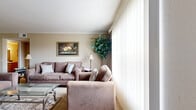This thoughtfully designed single-floor residence offers a complete and functional layout across its one bedroom and one bathroom. The living room serves as the heart of the home, featuring warm beige walls, crown molding, and large floor-to-ceiling windows dressed with vertical blinds that flood the space with natural light. The open, carpeted living area provides ample room for seating arrangements and opens to a welcoming ambiance accented by hardwood-style flooring in select areas. The kitchen is a galley-style space with warm wood cabinetry, speckled countertops, hardwood-style flooring, and white appliances including a range, refrigerator, and dishwasher — offering efficient use of space and practical storage. The bedroom is a comfortable retreat featuring soft carpet, a ceiling fan, and a window that allows natural light to filter in. The full bathroom includes a wood-toned vanity with a granite-style countertop, hardwood-style flooring, and a shower-tub combination. Throughout the residence, neutral tones and consistent design choices create a cohesive, cozy atmosphere that is both practical and inviting.