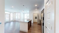 The Santa Barbara is a well-appointed one-bedroom, one-bathroom residence designed with a modern, open-concept layout. The kitchen serves as the centerpiece of the living space, featuring a large granite-topped island with an undermount sink illuminated by contemporary pendant lighting. Dark espresso cabinetry extends to the ceiling, providing ample storage, while a full suite of stainless steel appliances—including a refrigerator, electric range, microwave, and dishwasher—and a subway tile backsplash complete the kitchen's polished aesthetic.

Wood-style plank flooring flows through the kitchen and into the open living area, which benefits from generous natural light through multiple windows and French doors that open to a private balcony. The bedroom features plush carpet, a ceiling fan with light fixture, and a window with outdoor views.

The bathroom offers dual undermount sinks set into a granite countertop with dark cabinetry below, a tub-shower combination, and wood-style flooring. Additional highlights include an in-unit washer with built-in shelving above, and recessed lighting throughout the main living areas, contributing to a clean, contemporary ambiance.