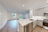 This well-appointed single-floor residence features 3 bedrooms, 2 bathrooms, and a thoughtfully designed open-concept layout that seamlessly connects the kitchen and living areas. The kitchen is a standout feature, showcasing a large center island with a white quartz countertop, undermount sink, stainless steel appliances including a French door refrigerator and built-in microwave, taupe cabinetry, and a built-in wine cooler — ideal for entertaining. The open living area is bathed in natural light through expansive windows and a sliding glass door that leads to a private balcony overlooking a landscaped courtyard. Light-toned hardwood flooring flows throughout the main living spaces, contributing to the home's clean, contemporary aesthetic. The bedrooms are well-sized, with the primary bedroom offering generous proportions and access to natural light. Both bathrooms are finished with warm wood vanities, white quartz countertops, large-format tile flooring, and glass-enclosed showers, reflecting a consistent modern design sensibility. A dedicated closet and multiple hallways provide practical storage and circulation throughout. Recessed lighting and neutral walls complete the bright, airy ambiance of this polished residence.