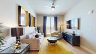 This thoughtfully designed one-bedroom, one-bathroom residence in Rancho Cordova, California offers a comfortable and functional single-floor layout. The open-concept living area serves as the heart of the home, featuring light-toned hardwood-style flooring, a ceiling fan, and large windows with blinds and drape panels that invite abundant natural light. The kitchen is well-appointed with taupe shaker-style cabinetry, stainless steel appliances including a French door refrigerator, electric range, and built-in microwave, all complemented by clean white quartz countertops. A peninsula with bar seating connects the kitchen seamlessly to the dining and living spaces, creating an ideal area for entertaining. The bedroom offers plush carpeting, a window with natural light, and direct access to the full bathroom, which features wood-toned cabinetry, a single-sink vanity, and wood-style flooring. Two closets provide generous storage, including a walk-in closet accessible from the bathroom. A dedicated in-unit laundry area adds everyday convenience. Throughout the residence, neutral warm-toned walls create a cohesive, inviting ambiance that complements the modern finishes found in every room.