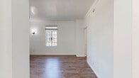 Located at 535 S Gramercy Place in the heart of Los Angeles, this efficiently designed single-floor unit offers a thoughtful layout that maximizes every square foot. The space includes a living room, kitchen, bathroom, two closets, and a dedicated entrance, all unified by warm hardwood-style flooring throughout.

The living room is bright and inviting, featuring crisp white walls, elegant crown molding, and multi-pane windows that allow generous natural light to fill the room. A classic wall sconce adds a charming touch, while a traditional cast-iron radiator contributes a sense of vintage character alongside modern updates.

The kitchen is clean and functional, outfitted with white shaker-style cabinetry, light countertops, a stainless steel sink, and a full suite of stainless steel appliances including a refrigerator, gas range, and microwave. A window above the counter provides additional natural light to the workspace.

A wide, light-filled hallway connects the rooms seamlessly, framed by large grid-pane windows and accented with wall molding details that echo the unit's classic architectural sensibility. The two closets offer practical built-in storage solutions, including a fitted closet with drawers and shelving. Crown molding, arched doorways, and panel doors throughout lend the space a cohesive, timeless aesthetic well-suited to city living.