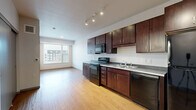 Located at 2941 Harriet Ave in Minneapolis, MN, this 1-bedroom, 1-bathroom unit offers a thoughtfully designed layout that maximizes every square foot of living space. The open-concept kitchen and living area is anchored by rich, dark-stained wood cabinetry with sleek hardware, dark granite-style countertops, and a full suite of black appliances including a range, microwave, dishwasher, and refrigerator. Track lighting overhead and warm wood-tone luxury vinyl plank flooring add both functionality and style to the space. A large window in the living area floods the room with natural light and provides views of the surrounding neighborhood. The entry area features additional wood-tone flooring and a built-in electrical panel, offering a clean and organized welcome into the unit. The bedroom is carpeted for comfort and features its own window for natural light, along with access to a generously sized walk-in closet outfitted with multi-level wire shelving and hanging rods for ample storage. The full bathroom is finished with large-format gray tile flooring, a dark wood vanity with a white countertop, a wide mirror, and a full soaking tub with shower. Clean, neutral walls throughout create a bright and versatile backdrop ready for personalization.