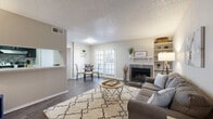 Located at Crystal Springs in Bedford, TX, this one-bedroom, one-bathroom residence offers a thoughtfully designed single-floor layout that maximizes comfort and functionality. The open-concept living, dining, and kitchen area serves as the heart of the home, featuring rich dark hardwood flooring, a textured ceiling, and a tile-surround wood-burning fireplace flanked by built-in shelving. French doors flood the space with natural light and provide a seamless connection to the outdoors, while a pass-through window links the kitchen to the living area for added convenience. The living room offers generous proportions, ideal for both relaxing and entertaining. The bedroom is a comfortable retreat, carpeted for warmth, with a large window that invites natural light and an outdoor view. Multiple closets throughout — including a spacious walk-in with wire shelving — provide exceptional storage for a home of this size. The bathroom features wood-look flooring, a clean white tiled tub-shower combination, and a grab bar for added accessibility. Neutral tones and soft grey walls carry throughout, creating a cohesive and inviting ambiance. With five closets total, this residence stands out for its remarkable storage capacity relative to its scale.
