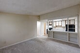 Located at 3829 Redan Rd in Decatur, GA, this one-bedroom, one-bathroom unit offers a practical and comfortable single-floor layout. The living room is a welcoming open space featuring neutral beige walls, soft wall-to-wall carpeting, a textured ceiling, and a wall-mounted HVAC unit beneath a window that brings in natural light. Built-in shelving connects the living area to the kitchen, adding a convenient display and storage element.

The kitchen is equipped with wood-look vinyl flooring, white cabinetry with dark wood upper accents, granite-style countertops, a stainless steel sink, a black electric range with overhead ventilation, and a black refrigerator. A skylight-style ceiling fixture brightens the space, and a doorway leads to a utility hallway housing the water heater.

The bedroom is a well-proportioned retreat with plush carpeting, a textured ceiling, and a window that allows natural outdoor views and light to fill the room. A closet door and a wall vent provide practical functionality.

The bathroom features a clean, all-white tub and shower combination with chrome fixtures and a safety grab bar. Two hallways connect the rooms efficiently, contributing to a straightforward and functional floor plan throughout the unit.