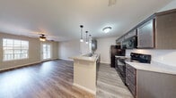 This single-story residence at 931 Megan Lane in Willard, Missouri offers a well-organized layout with a clean, neutral aesthetic throughout. The open-concept kitchen and living area serves as the heart of the unit, where dark espresso cabinetry pairs with light countertops and a peninsula with pendant lighting overhead. Black appliances, including a refrigerator, range, and over-the-range microwave, complement the kitchen's cohesive design. Light-toned hardwood-style flooring extends throughout the main living areas, creating a seamless, easy-to-maintain surface. Natural light filters in through windows and a glass-paneled exterior door in the living area, which also features a ceiling fan. A front entry door opens directly into the main living space, positioned adjacent to the kitchen peninsula. The bedrooms are finished with plush carpet and include ceiling fans and natural light from individual windows, with double-door closets providing ample storage. The bathroom is appointed with tile flooring in earthy tones, a vanity with a stone-look countertop, and a full tub-shower combination. Overall, the space maintains a consistent, understated palette with practical finishes throughout.