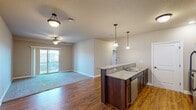 Located at 2807 Bobcat Dr in Ames, Iowa, this well-appointed 2-bedroom, 2-bathroom home offers a thoughtfully designed single-level layout. The open-concept kitchen and living area serves as the heart of the home, featuring warm hardwood-style flooring, rich dark wood cabinetry, granite countertops, and a peninsula with pendant lighting. Stainless steel appliances, including a refrigerator, range, and microwave, complete the kitchen. The living area is accented by a ceiling fan and sliding glass doors that open to a private balcony, filling the space with natural light and outdoor views.

The spacious primary bedroom includes a ceiling fan, carpeted flooring, and its own en-suite bathroom with a walk-in glass-door shower, dark-framed fixtures, and a wood-vanity with a white countertop. The second bedroom features plush carpeting, a sliding-door closet, and a window with outdoor views. The second bathroom offers a full tub-shower combination and a matching wood vanity. A dedicated laundry room with side-by-side washer and dryer and wire shelving adds everyday convenience. Neutral warm tones throughout give the home a clean, welcoming ambiance.