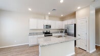 This two-story home offers a thoughtfully designed layout with clean, contemporary finishes throughout. The kitchen serves as a central highlight, featuring crisp white shaker-style cabinetry, light granite countertops, and a large center island with an integrated sink — ideal for both meal preparation and casual dining. A full suite of stainless steel appliances, including a French door refrigerator, electric range, and over-the-range microwave, completes the space. Light wood-look flooring runs through the main living areas, contributing to a bright and cohesive aesthetic.

The living area is open and airy, with large windows fitted with blinds that allow for natural light while maintaining privacy. Ceiling fans are present throughout the bedrooms, enhancing comfort year-round. The carpeted bedrooms offer a soft, warm feel and include generous closet space, with at least one walk-in closet featuring built-in shelving and hanging rods for ample storage.

The bathrooms are well-finished, with the primary bathroom showcasing a wide double-sink vanity with granite countertops, large mirrors, and light wood-look flooring. A secondary bathroom provides a full tub-shower combination with tile surround, a granite-topped vanity, and wood-look flooring. The overall palette of warm neutrals and white trim gives the home a clean, move-in-ready appeal.