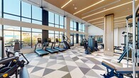 This well-appointed fitness center offers an expansive, open exercise space designed with both function and aesthetics in mind. The room is defined by soaring double-height floor-to-ceiling windows that wrap around the perimeter, flooding the interior with abundant natural light and providing sweeping views of the surrounding urban skyline. The architectural design strikes a refined balance between contemporary and warm elements, featuring a distinctive wood-paneled ceiling with integrated linear LED lighting that creates a bright, energizing atmosphere throughout.

The flooring is covered in a striking geometric-patterned tile in muted tones of gray, white, and taupe, adding visual depth to the open layout. The exercise area is comprehensively equipped with a dedicated cardio zone featuring multiple treadmills, stair climbers, and elliptical machines, all positioned to take full advantage of the panoramic outdoor views. A strength training section houses a full rack of dumbbells, adjustable benches, and a variety of cable and resistance machines. Full-length mirrors are positioned along the walls to maximize sightlines and enhance the sense of openness. Warm wood columns and accents throughout tie the space together, reinforcing its polished, modern character.