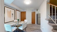 This two-story, two-bedroom, two-bathroom home in Woodbury, Minnesota offers a well-organized layout spread across two floors. The main level features wood-look plank flooring throughout, a bright and open living room filled with natural light from sliding glass doors, and a dedicated dining area with warm wood-toned doors and access to the kitchen. The kitchen is well-appointed with white shaker-style cabinetry, white quartz countertops, a subway tile backsplash, a stainless steel appliance suite including a refrigerator, range, microwave, and dishwasher, and a window overlooking the exterior. A convenient half bathroom is also located on the main floor, featuring gray cabinetry and a vanity with under-cabinet storage. Upstairs, the spacious primary bedroom benefits from vaulted ceilings, large windows that invite ample natural light, soft carpet flooring, and a generous closet with sliding wood-grain doors. The second bedroom is equally comfortable, with vaulted ceilings, carpet, and its own closet. The full upper bathroom features a wide vanity with white cabinetry, a large mirror, and wood-look flooring. A staircase connects the two levels, completing this functional and stylish two-floor layout.